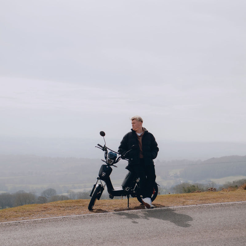 A rider on an Eskuta SX-250 on a country road, looking out over the hills