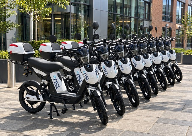 A row of Eskuta SX-250s in NSL livery with top boxes, lined up outside an office building