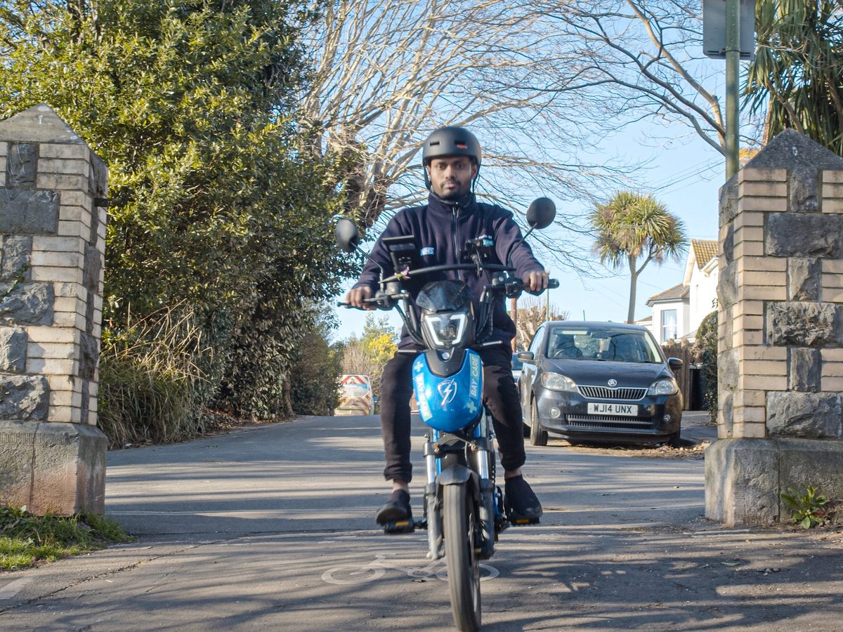 A rider on a blue Eskuta SX-250 on a tree-lined road