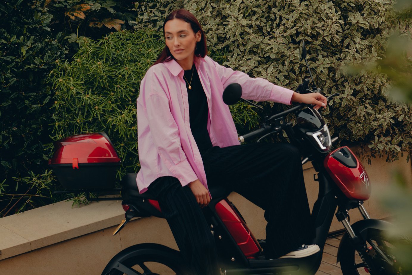 A rider in a pink shirt on a red Eskuta SX-250 Tourer with its colour-matched top box