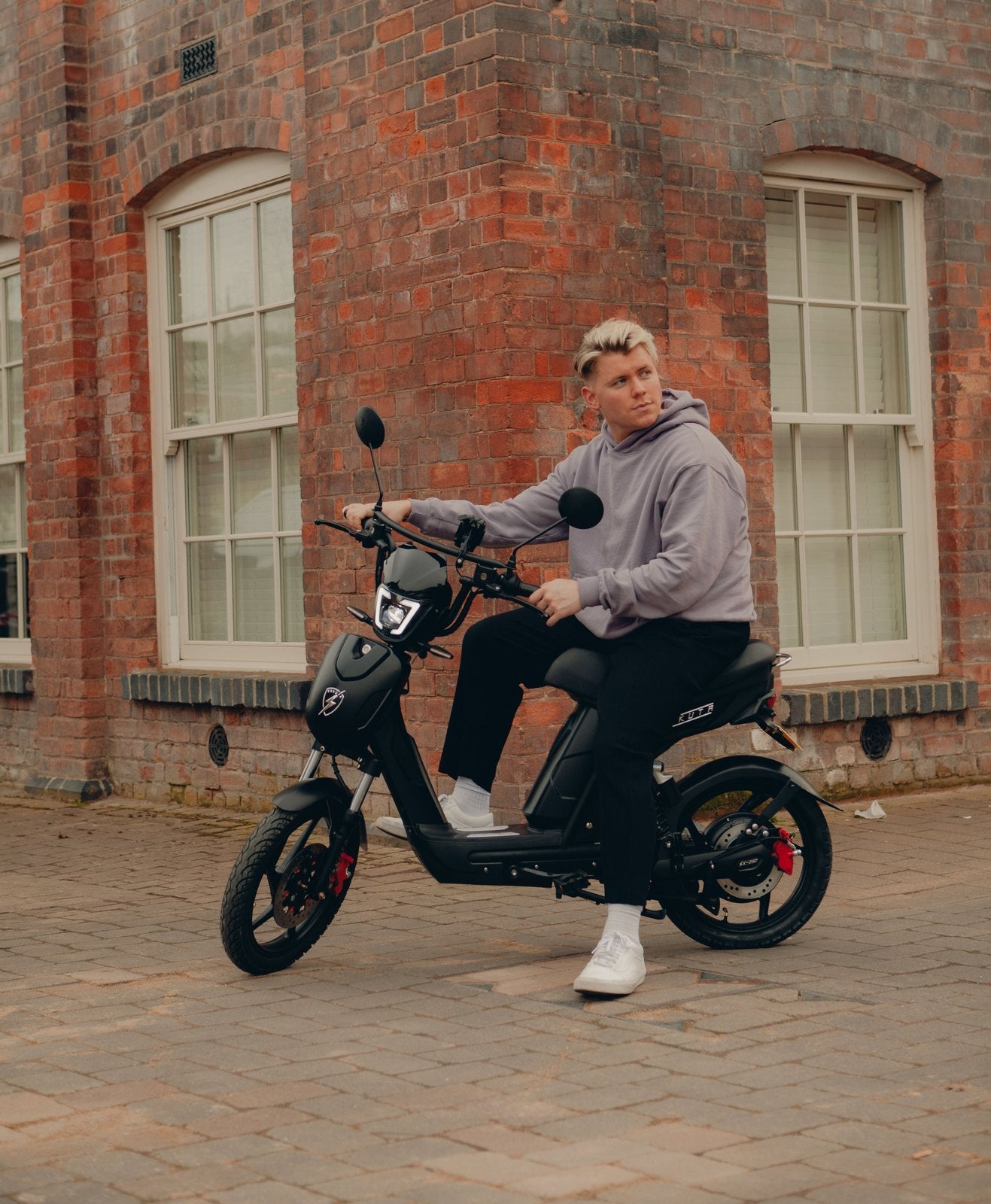 A rider on a black Eskuta SX-250 Classic outside a brick building