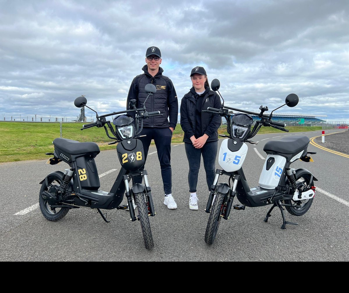 Two uniformed fleet riders standing with their numbered Eskuta SX-250s on site