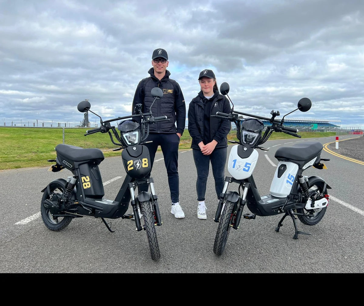 Two uniformed fleet riders standing with their numbered Eskuta SX-250s on site