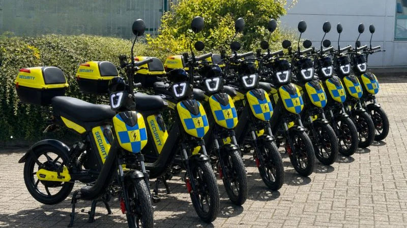 Ten Eskuta SX-250s in Battenburg security livery lined up outside a commercial building, each with a branded top box